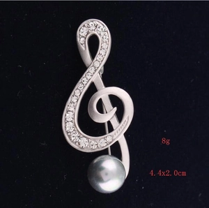 Detailed macro view of a musical treble clef brooch with grey pearl and crystal inlay