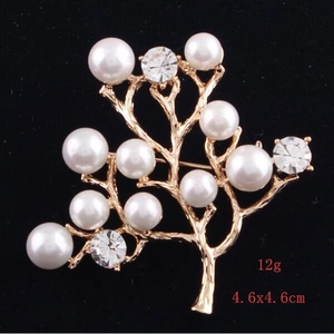 Detail showing the 4.6x4.6cm tree-shaped gold brooch with pearls and crystals