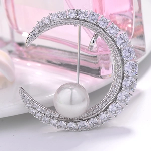 Elegant crescent moon pearl brooch with sparkling cubic zirconia on a white plate