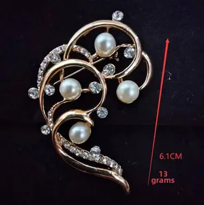 Detail view of a 6.1cm gold flower brooch with white pearls and sparkling rhinestones