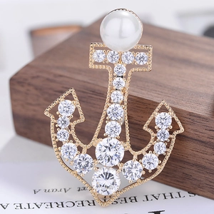 Macro shot of gold anchor brooch with white zircon paving and elegant pearl detail
