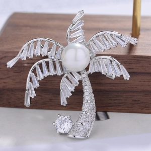 Elegant palm tree brooch with silver zircons and a central pearl on a wooden display