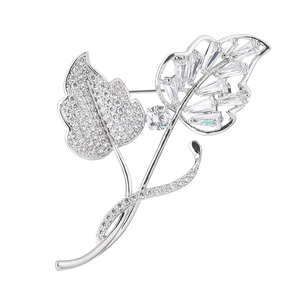 Elegant silver leaf brooch with pave-set crystals and central gemstone on white background