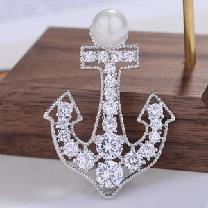 Macro shot of a luxury anchor brooch featuring sparkling zircons and a large white pearl
