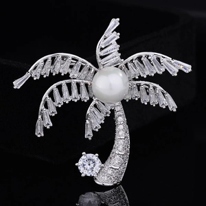 Elegant coconut tree brooch with sparkling zircons and pearl on a black reflective background