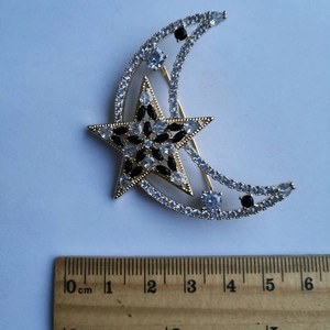 Vue macro d'une broche étoile et lune dorée avec cristaux et règle de mesure