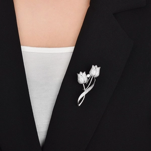 Détail d'une broche tulipe en argent avec zircons brillants sur un blazer noir