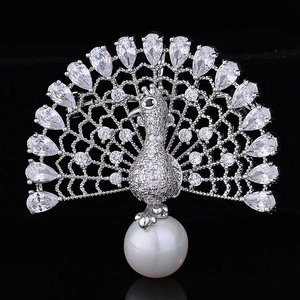 Macro shot of silver peacock brooch with pavé zircon stones and a large white pearl