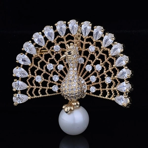 Detailed close-up of a gold peacock brooch with white zircons and a large pearl drop