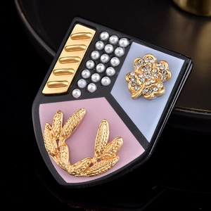 Vue rapprochée de la broche bouclier avec perles, relief de laurier doré et diamants