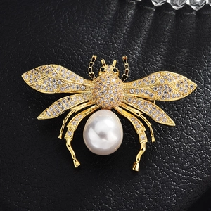 Goldene Bienenbrosche mit Zirkonia-Flügeln und weißer Perle auf schwarzem Leder