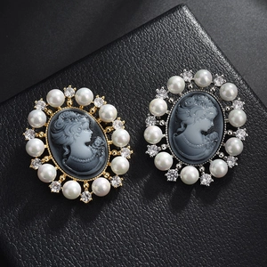 Vue détaillée de broches camée vintage avec perles et zircons sur fond de cuir noir