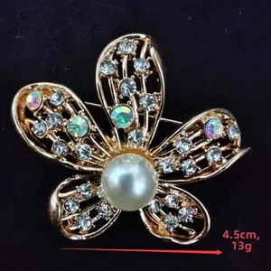 Macro detail of 4.5CM golden flower brooch with rhinestones and central pearl inlay