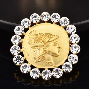 Détail macro d'une broche dorée avec relief grec et cristaux de strass brillants