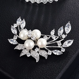 Détail macro d'une broche en argent avec quatre grandes perles blanches et zircons