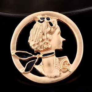 Vue macro d'une broche vintage dorée avec silhouette de profil féminin et émail noir