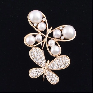 Elegant gold double butterfly brooch featuring white pearls and shimmering rhinestones