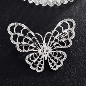 Détail macro de broche papillon argentée avec zircons sur cuir noir texturé