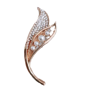 Elegant rose gold leaf brooch with white pearls and sparkling crystals on white background