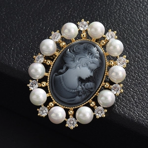 Détail macro d'une broche camée ornée de perles et cristaux sur monture dorée élégante
