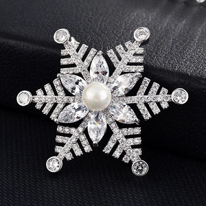 Détail macro de broche flocon d'argent avec oxydes de zirconium et perle blanche centrale