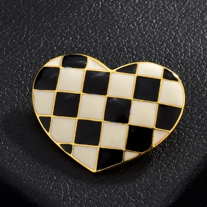 Gros plan d'une broche en forme de cœur avec motif à damier noir et blanc et bords dorés