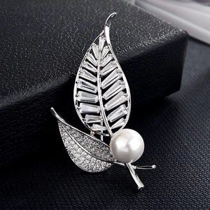 Détail macro d'une broche feuille argentée avec zircons rectangulaires et une perle blanche
