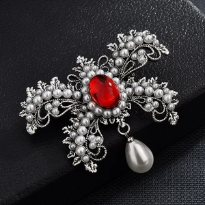 Détail de broche vintage argentée avec pierre rouge et perles blanches sur cuir noir
