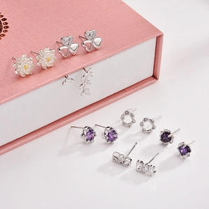 Close-up of S925 silver stud earring set with daisy and heart motifs in a pink jewelry box