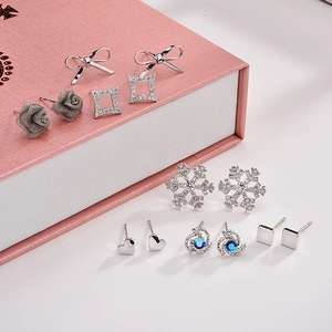 Detailed set of silver stud earrings featuring bows, roses, and crystals in a gift box