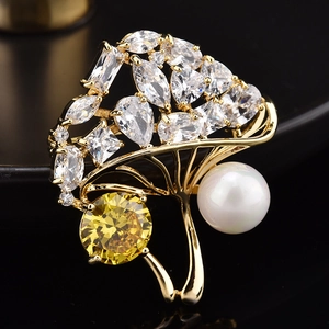 Macro d'une broche arbre dorée avec cristaux, pierre jaune et perle blanche