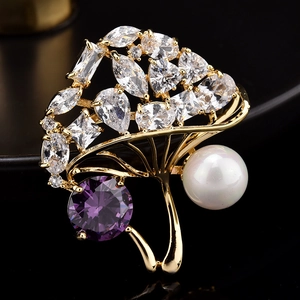 Détail d'une broche en forme d'éventail doré avec zircon violet et perles blanches