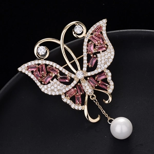 Élégante broche papillon avec pierres roses et perle pendante sur fond noir texturé