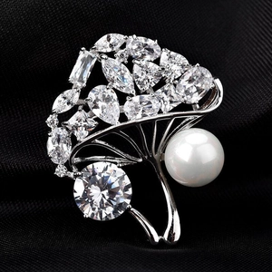 Détail macro de broche bouquet avec perle blanche et zircon sur satin noir élégant