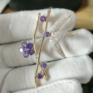 Detail of bamboo shaped brooch with gold plating, purple gemstones and zircon leaves