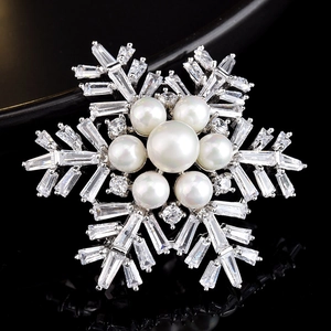 Détail macro d'une broche flocon de neige avec perles et zircone sur fond noir