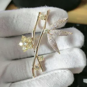 Detail of golden bamboo brooch with white zircons and yellow gemstones on leaf