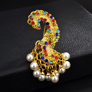 Gros plan d'une broche vintage dorée ornée de strass colorés et de perles blanches