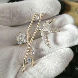 Detailed close-up of a gold bamboo leaf brooch featuring sparkling zircon inlay details