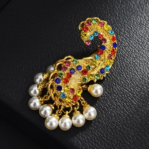 Gros plan d'une broche paisley dorée avec strass multicolores et pendentifs perles
