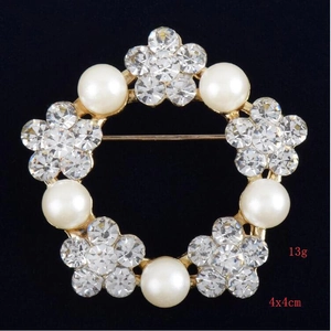 Gros plan détaillé d'une broche florale de 4x4cm avec perles et cristaux sur base dorée