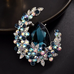 Detailed close-up of a crescent brooch with deep blue teardrop gem and pavé rhinestones