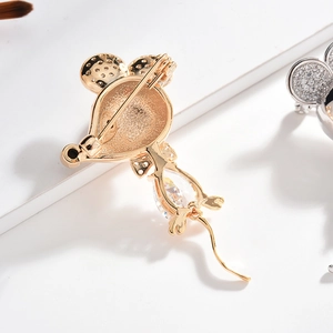 Elegant gold mouse brooch with clear teardrop zircon and safety pin on white background