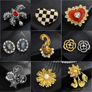 Variété élégante de broches or et argent avec perles et strass sur fond noir profond