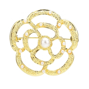 Broche fleur dorée élégante avec perles blanches et pétales creux sur fond blanc