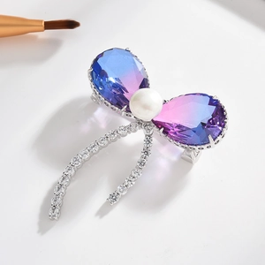 Élégante broche papillon avec zircon, cristaux, perle et pompons sur fond blanc