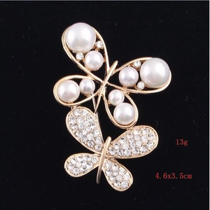 Vue macro d'une broche papillon dorée avec perles et strass sur velours noir