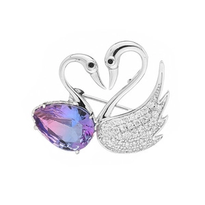 Macro shot of twin swan brooch with purple-blue gradient gemstone and micro-pave crystals