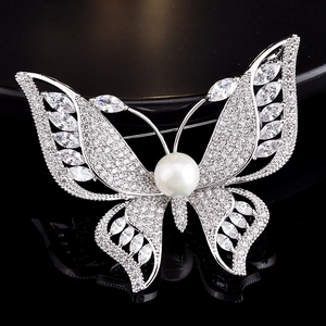 Macro shot of silver butterfly brooch featuring cubic zirconia and central pearl detail