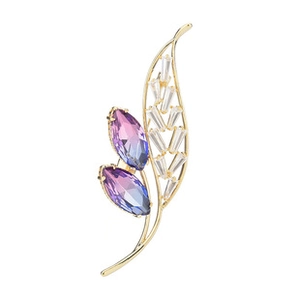 Macro view of floral brooch with purple gradient gemstones and golden metal finish